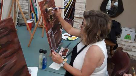 woman painting flower on canvas