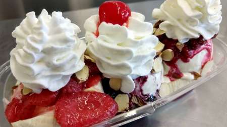 3 scoops of ice cream with fruit, whipped cream and cherry on top