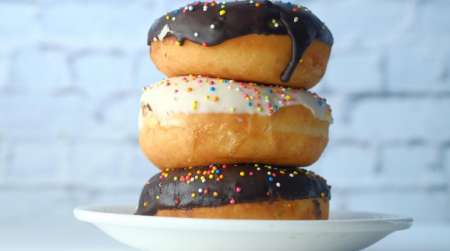 3 donuts stacked, 2 chocolate glazed & 1 vanilla glazed