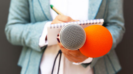 Close-up of reporter with notepad and recording device