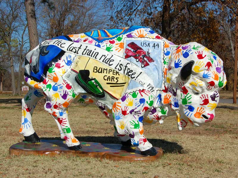Painted buffalo sculpture covered in multi-colored handprints. With text that reads, "the last train ride is free!"