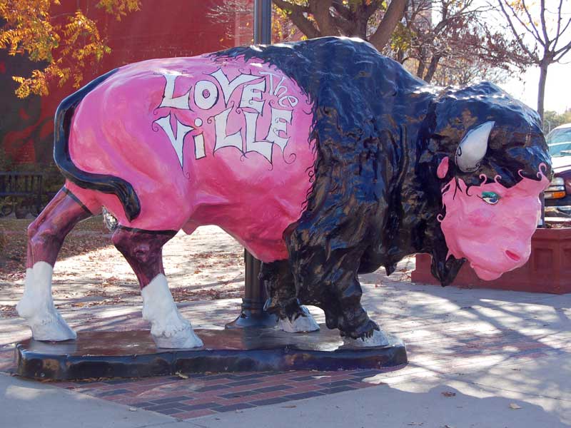 Pink painted buffalo sculpture with eyeliner. "Love the Ville" written on it. 