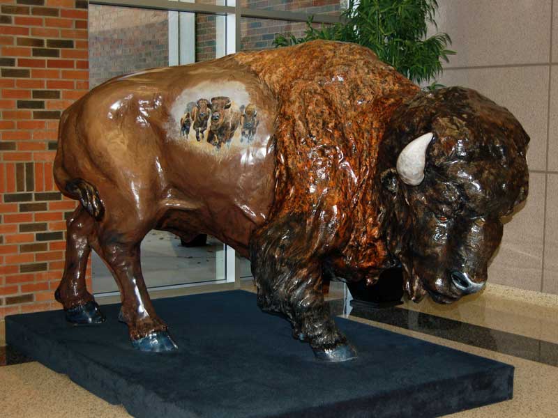 Icon of the American West Painted buffalo sculpture with scene of stampeding buffalo