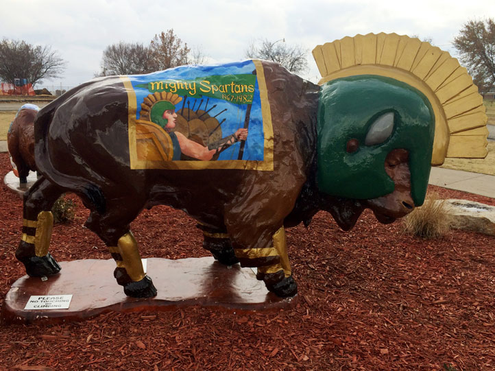 Sparty Painted buffalo sculpture wearing green and yellow spartan helmet.