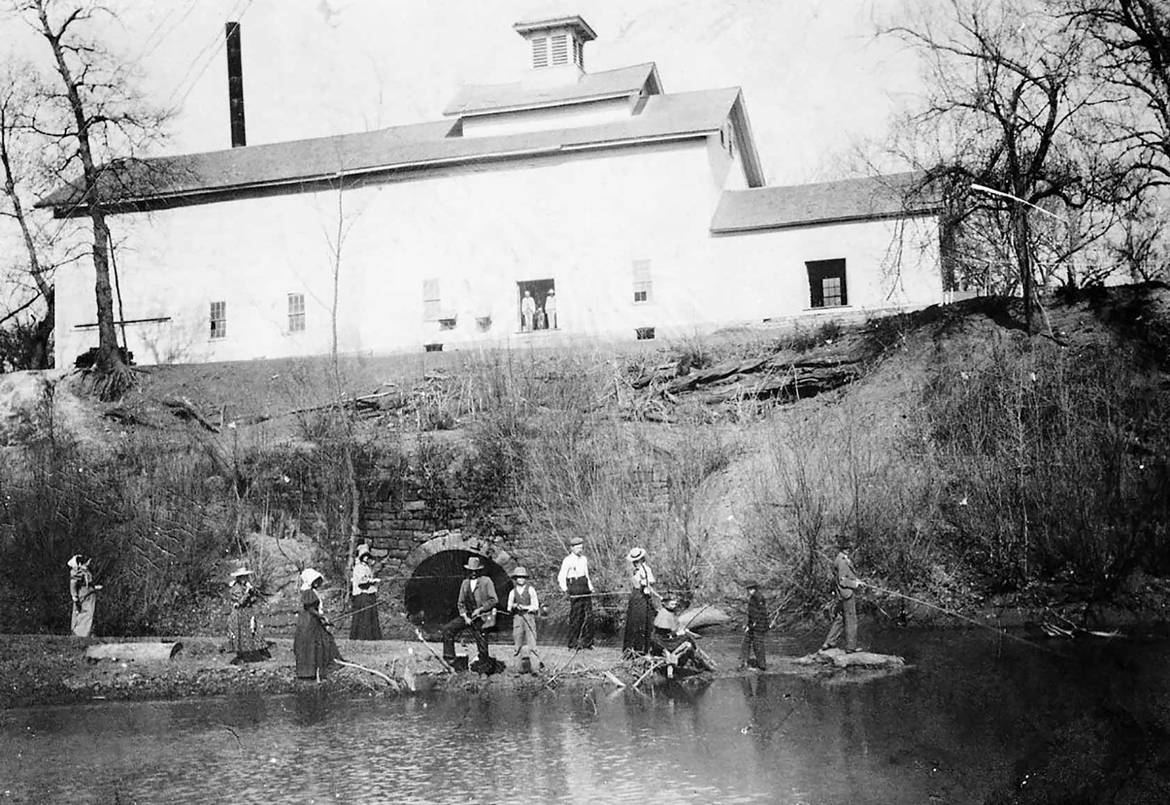 People fish and pose for a photograph in front of the millsite taken from the Caney River below.